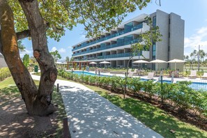 Un hôtel moderne doté d’une piscine, d’un espace extérieur aménagé et offrant une vue sur un ciel dégagé.