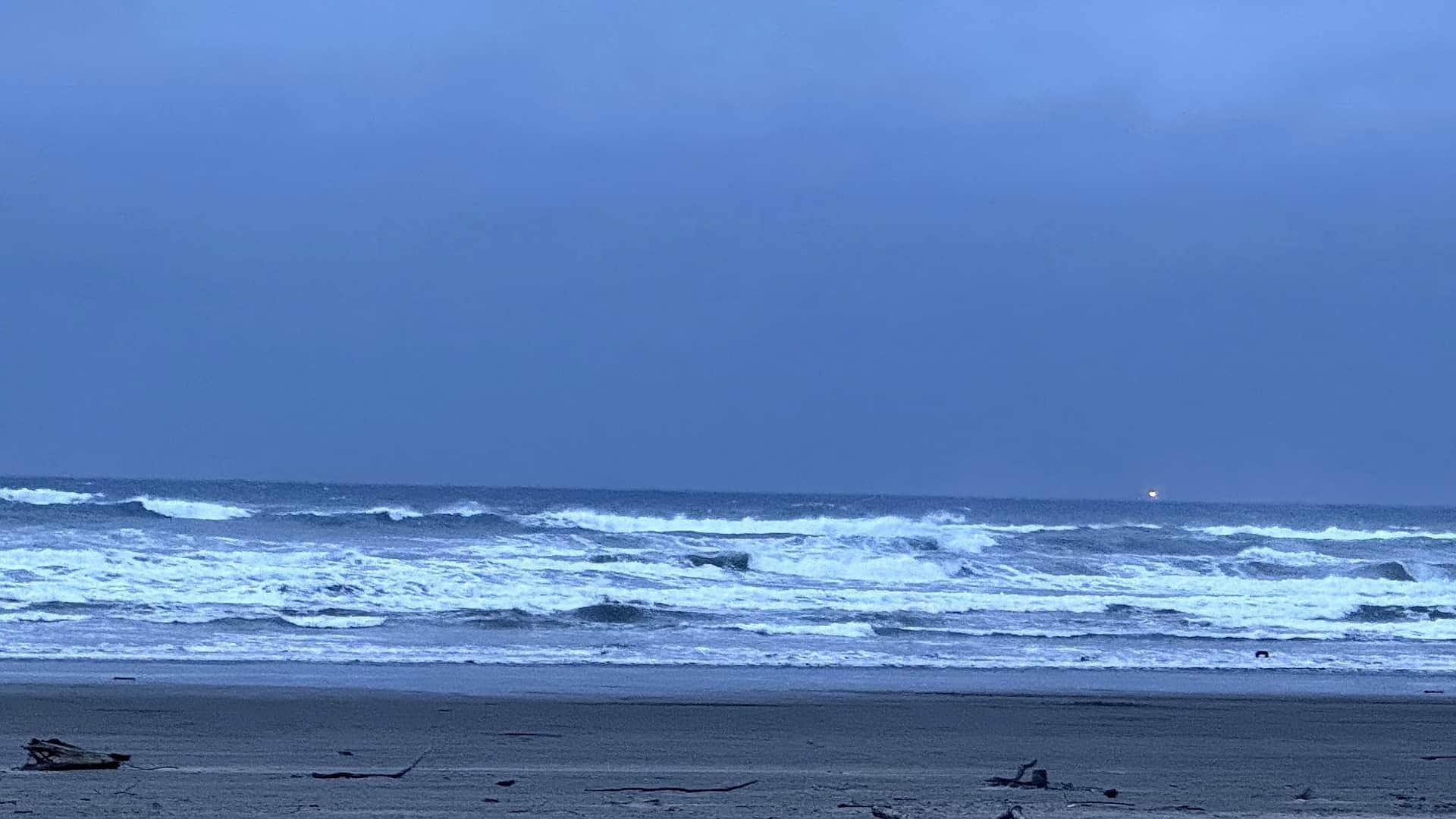 A beach with rough waves and a clear sky.