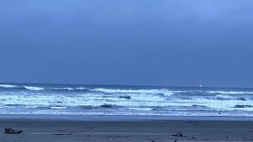 A beach with rough waves and a clear sky.