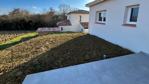 A residential property with a paved driveway, a small garden area, and a detached house with a tiled roof.