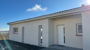 A modern single-story building with a flat roof, a door, and two windows.