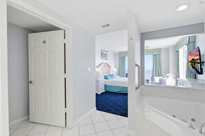 Ett hotellrum med en stor säng, ett badrum med badkar och utsikt över havet.