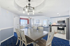 A dining area with a wooden table and chairs, a chandelier, and a view to the outside. - *New Listing!* Ocean Front Paradise; Stunning 2BR with Private Double Balcony at The Wyndahm #2321 (Daytona Beach)