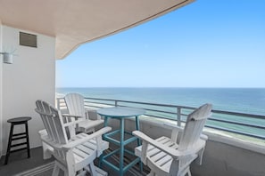 A balcony with white Adirondack chairs, a small round table, and a view of the ocean. - Beautiful 3 BR Direct Oceanfront Condo with Private Balcony at The Wyndham Ocean Walk Resort #2125 (Daytona Beach)