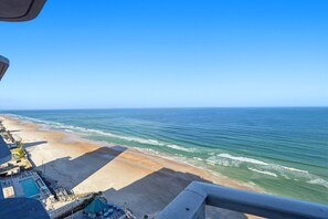A beach view from a balcony with a pool and umbrellas. - Beautiful 3 BR Direct Oceanfront Condo with Private Balcony at The Wyndham Ocean Walk Resort #2125 (Daytona Beach)