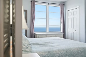 A bedroom with a large window, a bed, a bedside table, and a wardrobe. - Beautiful 3 BR Direct Oceanfront Condo with Private Balcony at The Wyndham Ocean Walk Resort #2125 (Daytona Beach)