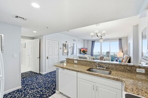 A modern kitchen with granite countertops, white cabinets, and a view of the balcony. - Beautiful 3 BR Direct Oceanfront Condo with Private Balcony at The Wyndham Ocean Walk Resort #2125 (Daytona Beach)