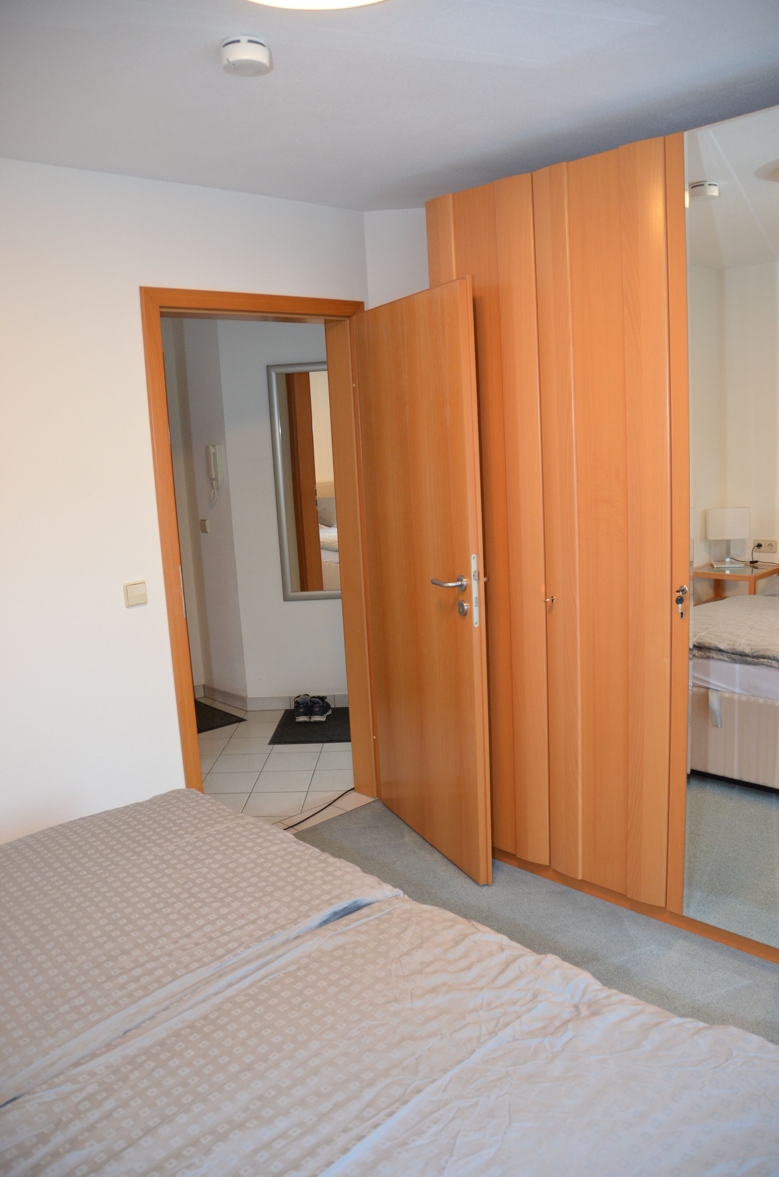 A bedroom with a bed, a wardrobe, and a mirror.
