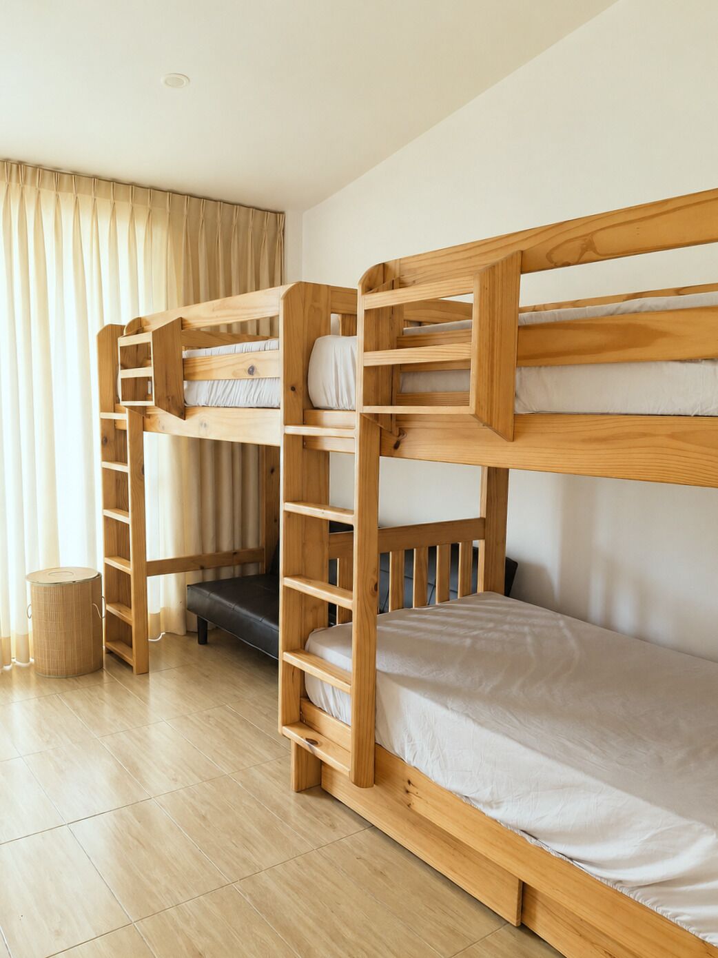Une chambre avec un lit superposé, une échelle, une petite table et une poubelle.