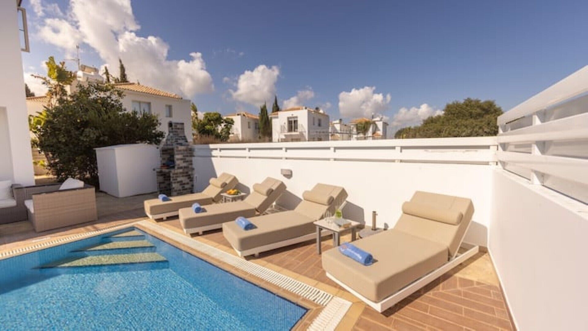 A rooftop pool area with lounge chairs and a stone fireplace.