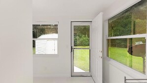 Um quarto com uma grande porta de vidro deslizante que dá para um quintal.