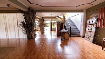 Un pasillo amplio con suelo de madera, una escalera y un panel en la pared con varios objetos.