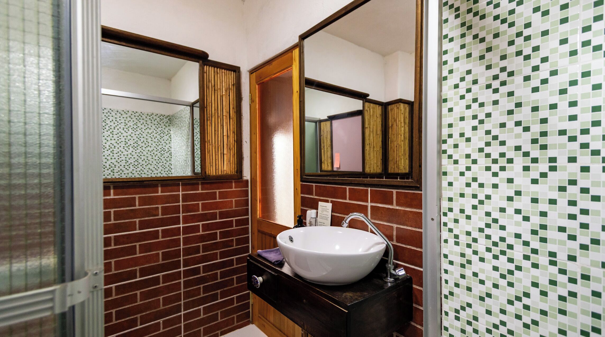 A bathroom with a white sink, a mirror, and a tiled wall.