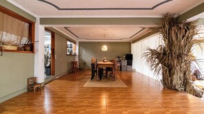 A dining area with a wooden table and chairs, a hanging light fixture, and a large plant. - La Cocina Bonita (San Pedro La Laguna)