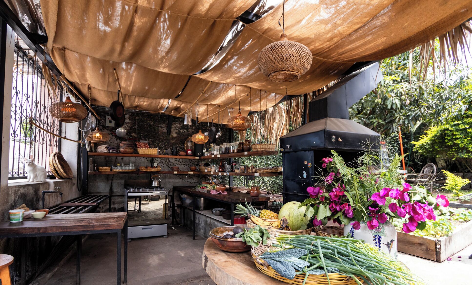 Un mercado al aire libre con varios puestos, una estufa negra y un gato en un alféizar.