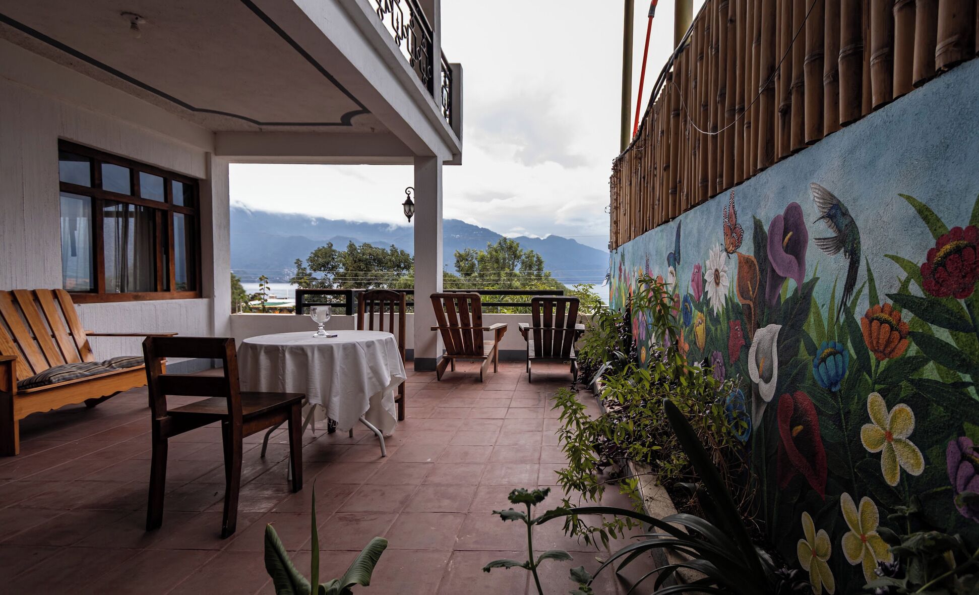 A covered outdoor seating area with a view of mountains and a painted mural of flowers.