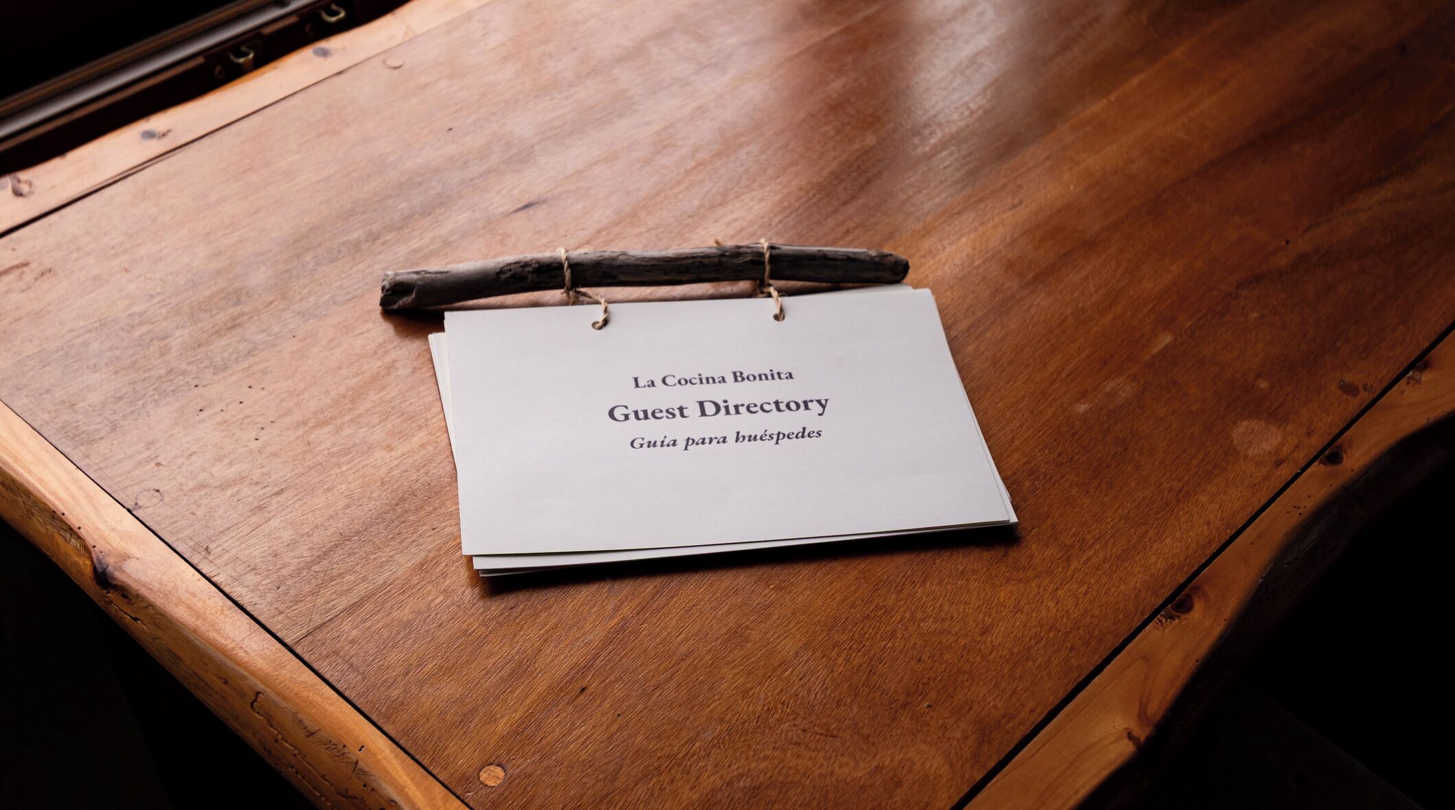 Una mesa de madera con un cartel blanco que dice 'Guest Directory' y 'La Cocina Bonita'.