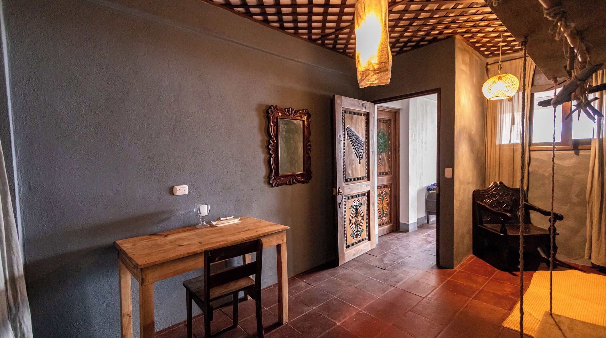 A hallway with a wooden table and chair, a mirror, and a door with decorative panels.