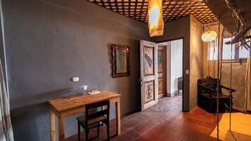 A hallway with a wooden table and chair, a mirror, and a door with decorative panels.