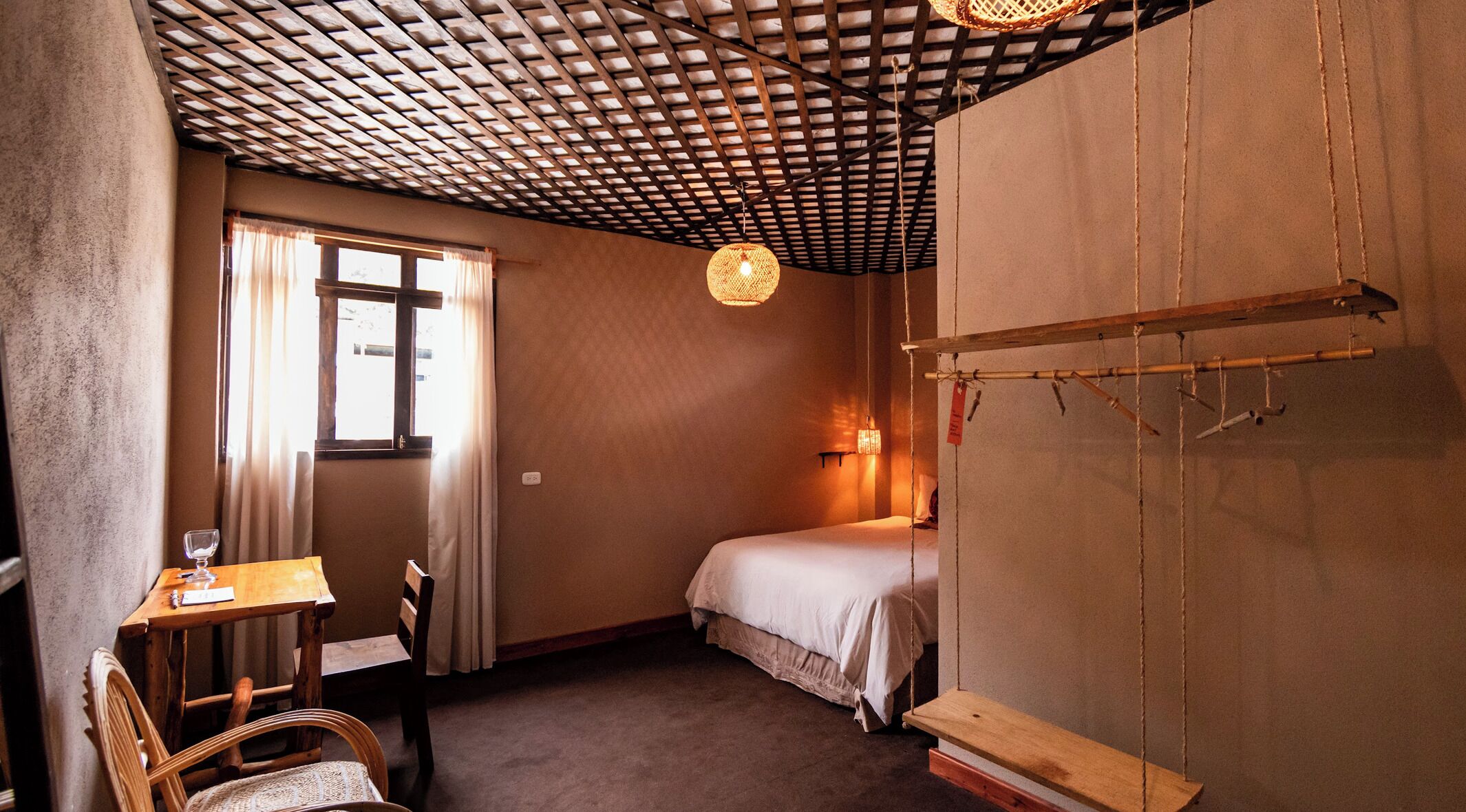 Ein Zimmer mit einem Bett, einem Schreibtisch und einer Hängelampe.