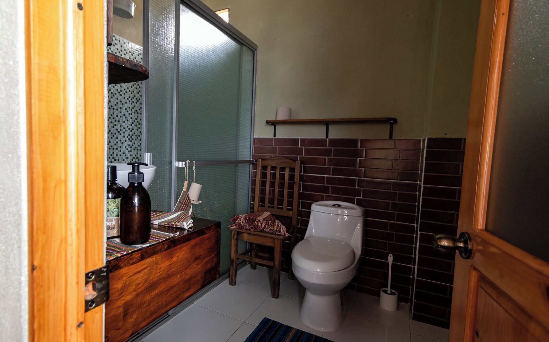 A bathroom with a wooden vanity, a toilet, and a shower area.