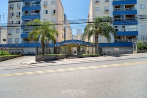 A residential building named 'San Fernando' with a gated entrance, multiple balconies, and palm trees. - 1-bedroom Apt in Floripa Oan0305 (Florianópolis)