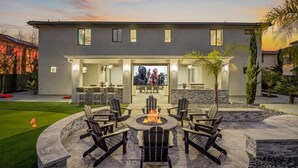 A modern house with a patio area featuring outdoor seating and a fire pit. - Luxe 7BR|Game Room, Firepit & Mini-putt| Sleeps 22 (Fresno)