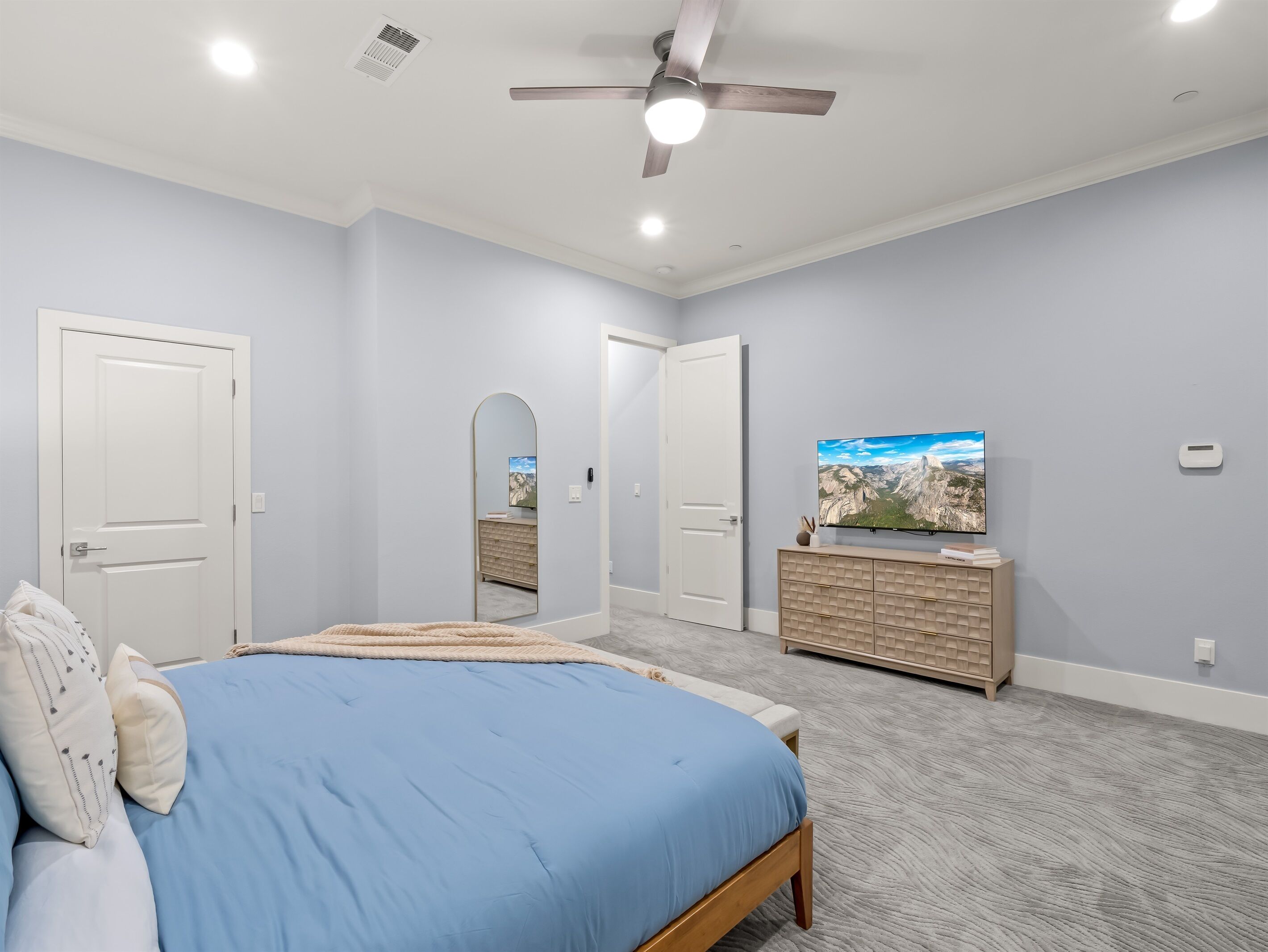 Une chambre à coucher avec un lit, une commode, un téléviseur et un ventilateur de plafond.
