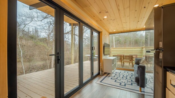 A modern kitchen with large sliding glass doors leading to a deck, wooden flooring, and a built-in refrigerator. - Shipping Container at Double Nickel Farm (Hurricane)