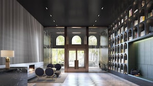 A modern lobby with a checkered floor, a reception desk, a seating area, and a bookshelf.