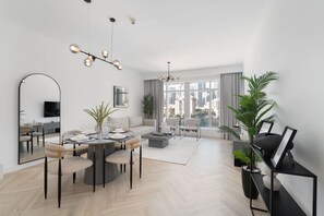 A modern living room with a dining area, large windows, and a city view. - Stayshort - Luxury 1 Bedroom in Downtown With Burj Khalifa View (Dubai)