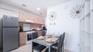 A modern kitchen with a refrigerator, stove, and dining table set for four. - Stayshort - Peaceful Studio in Production City That Sleeps 3 (Dubai)