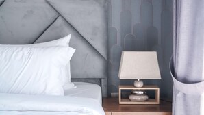A neatly made bed with white linens and a headboard with a geometric design. - Stayshort - Peaceful Studio in Production City That Sleeps 3 (Dubai)