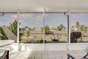 A covered outdoor area with a view of a residential neighborhood, including houses and palm trees. - Waterfront Gulf Access Beach House w Lainai (Port Charlotte)