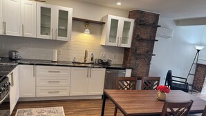 A modern kitchen with white cabinets, a black countertop, and a dining area with a wooden table and chairs.