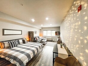 A modern bedroom with a large bed, a sofa, and a desk area.