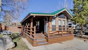 A wooden cabin with a green roof, a porch, and a picnic table. - #84 Tiger Run (Breckenridge)