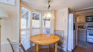 A dining area with a round wooden table, chairs, a hanging light fixture, and a kitchen in the background. - #84 Tiger Run (Breckenridge)