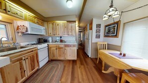 A compact kitchen with wooden cabinets, a stove, and a dining area with a table and chairs. - #244 Tiger Run (Breckenridge)