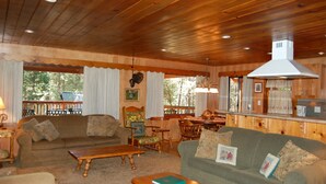 A cozy cabin interior with wooden walls and ceilings, a dining area, and a living room with a sofa and coffee table. - Deer Den (Yosemite National Park)