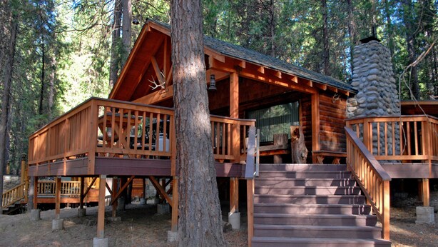 A wooden cabin with a deck, stairs, and a stone chimney. - Deer Den (Yosemite National Park)
