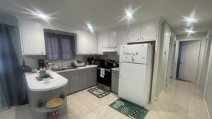 A compact kitchen with white cabinets, a built-in oven, and a refrigerator with a 'WELCOME!' magnet.