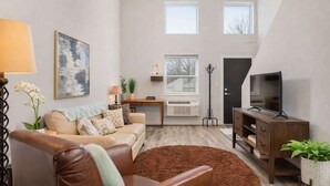Ein Wohnzimmer mit Sofa, Couchtisch, TV-Schrank, Lampe und einem Gemälde.