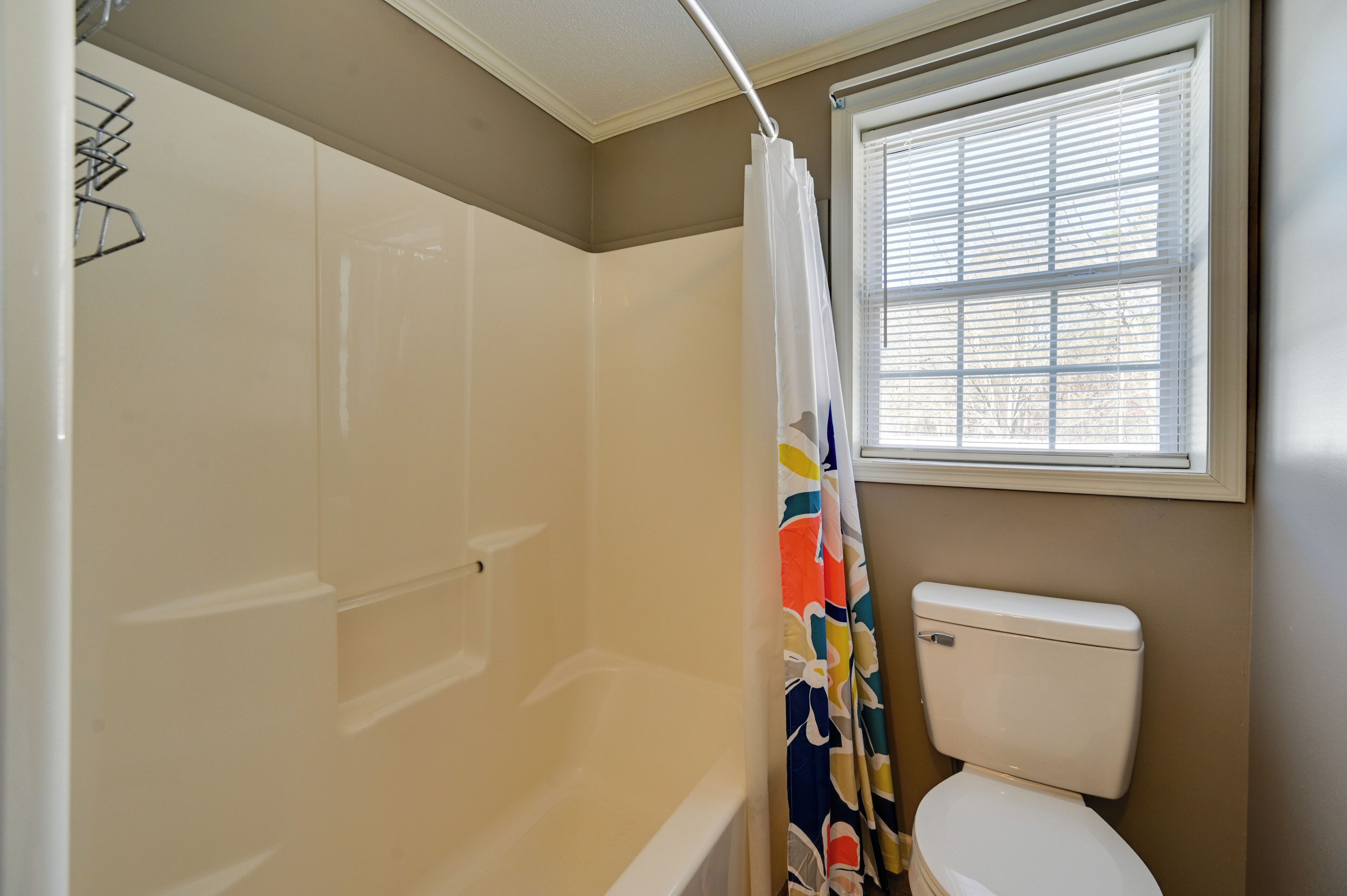 Ein Badezimmer mit Badewanne, Toilette und Fenster mit Jalousien.