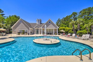 A swimming pool with a fountain, surrounded by lounge chairs and a house in the background. - Golf Cart & Pool Access! Condo in Myrtle Beach (Myrtle Beach)