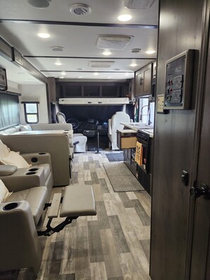 Ein kompaktes Wohnmobil-Interieur mit einer Küchenzeile, einer Sitzecke und einem kleinen Badezimmer.