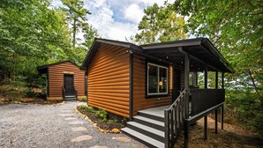 A log cabin with a porch and a separate cabin labeled "Secret Cinema." - Intimate Couples Hideaway  Theater + Hot Tub (Sevierville)