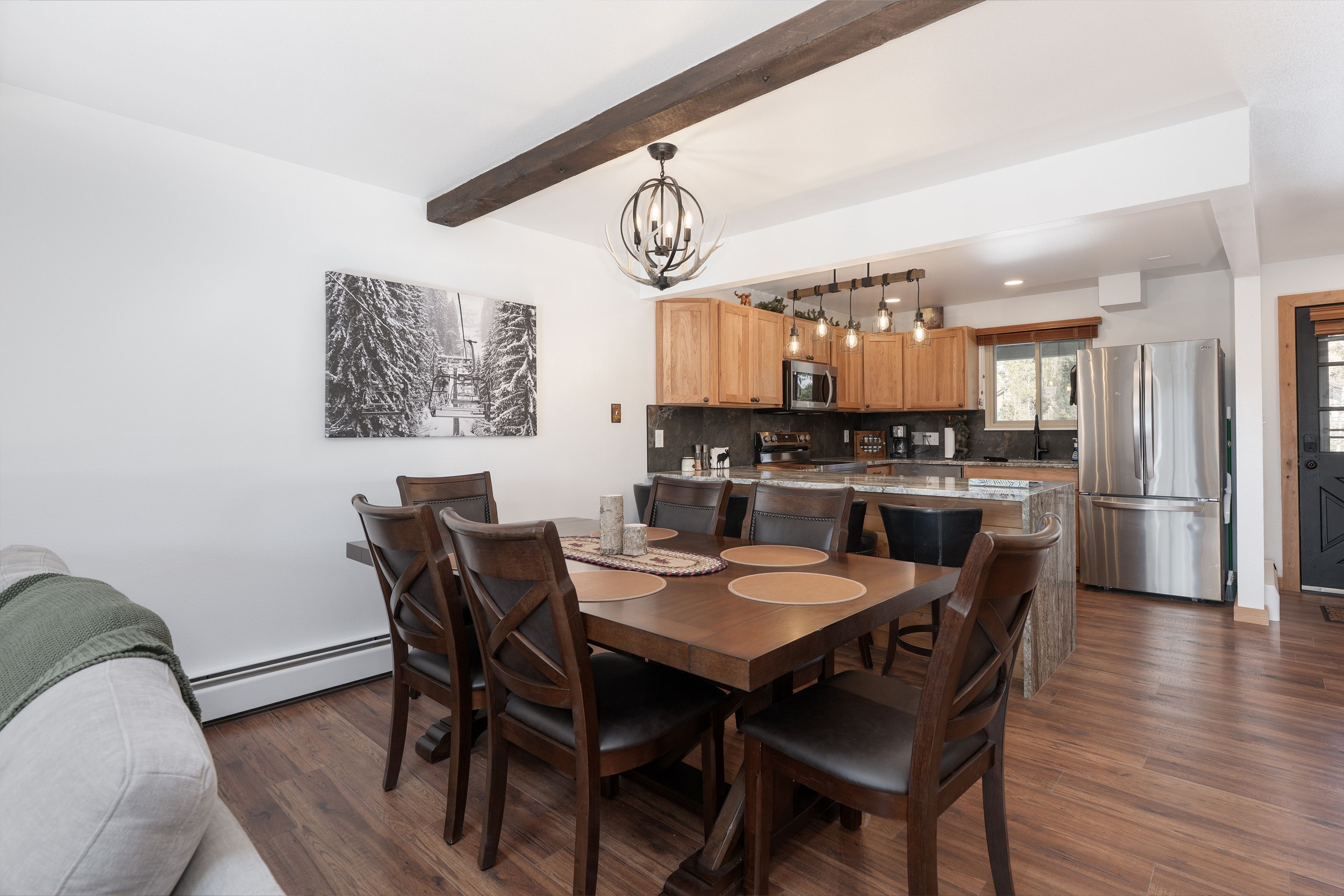 Una cocina moderna con armarios de madera, electrodomésticos de acero inoxidable y un comedor con mesa y sillas de madera.