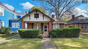A two-story house with a front porch, brick exterior, and a small front yard with hedges.