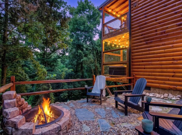 A wooden cabin with a fire pit and outdoor seating area. - Family Cabin | Hot Tub | Game Room | Fire Pit (Sevierville)